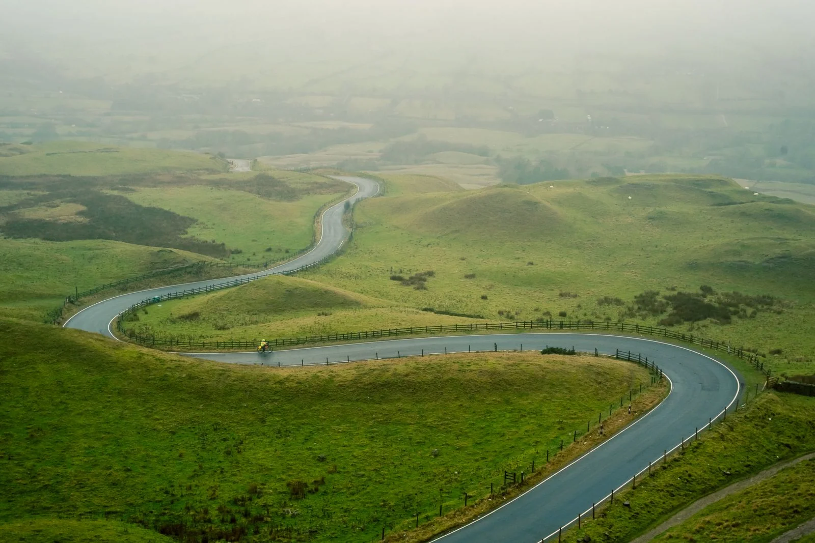 A cyclist on a winding road in the English countryside